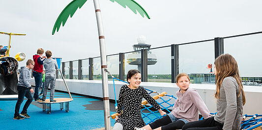 Kinder sitzen auf der Palmenschaukel auf der Aussichtsterrasse