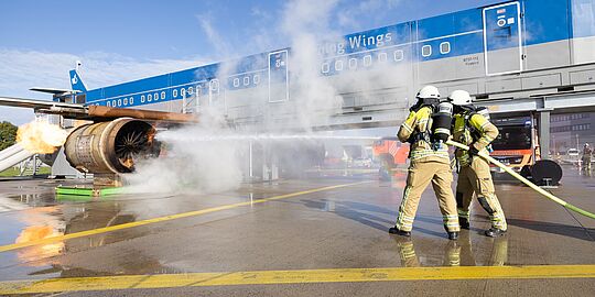 Feuerwehrmänner löschen einen Brand am Triebwerk