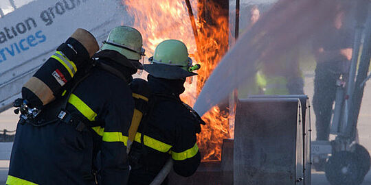 Übungsfoto: Zwei Feuerwehrleute löschen einen Fahrwerksbrand